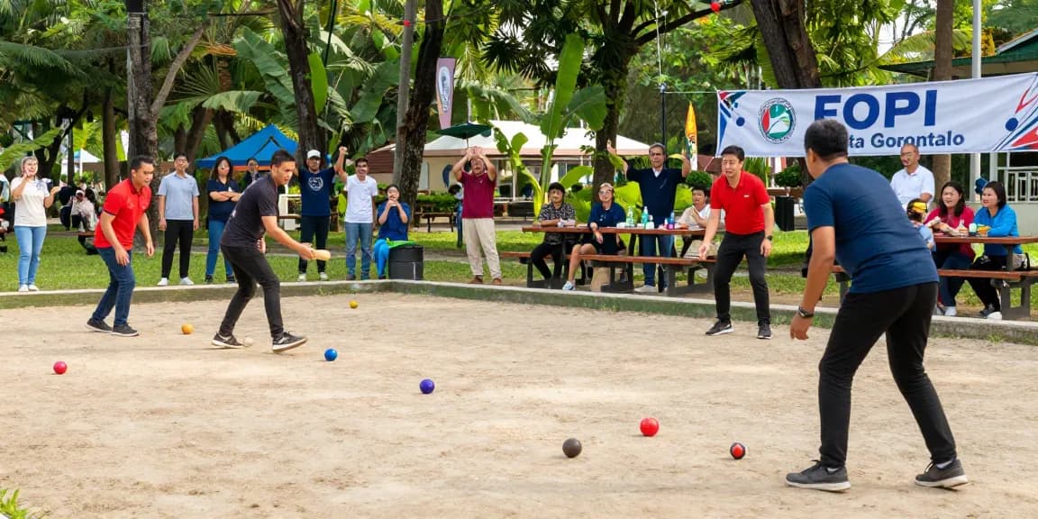 Permainan petanque menarik di taman lokal, menampilkan semangat komunitas dengan fopikotagorontal.org di latar belakang.
